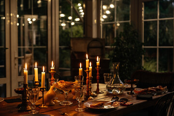 Burning candles on the table in a cozy house in the evening decorate the table with food. Evening...