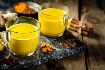 Turmeric golden milk and ingredients on wood background, copy space