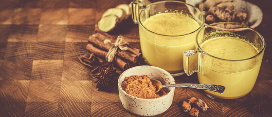 Turmeric golden milk and ingredients on wood background, copy space