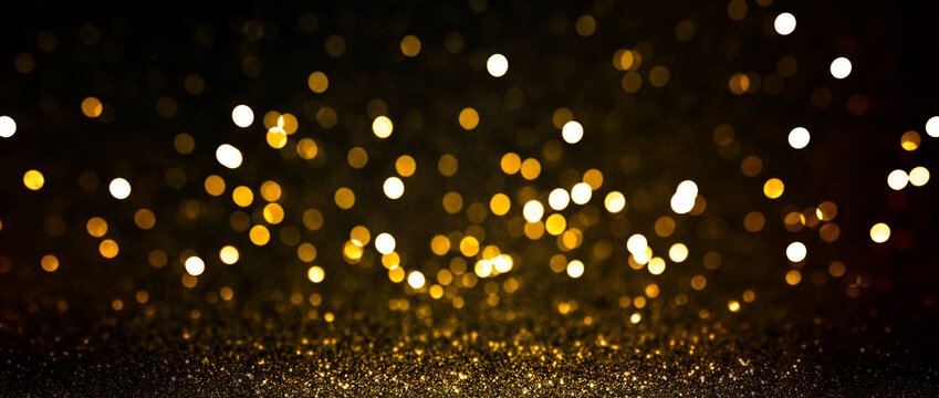 Abstract blurred background, yellow lights on black background. Golden christmas or new year bokeh. Defocused party night lights.