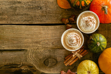 Fototapeta premium Pumpkin spiced latte in orange glasses on wood background, copy space