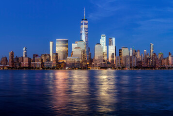 Obraz premium Manhattan skyline at dusk with city lights reflected in water, New York City, USA.