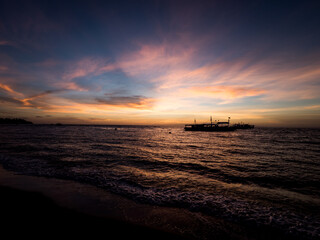 Fototapeta na wymiar Stunning sunrise over the beach in Philippines. Diving boats waiting for early morning divers.