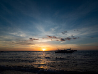 Naklejka na ściany i meble Stunning sunrise over the beach in Philippines. Diving boats waiting for early morning divers.