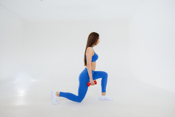Sexy young girl performs sports exercises on a white background. Fitness, healthy lifestyle