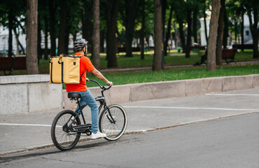 City delivery. Courier in helmet with big backpack rides on bicycle