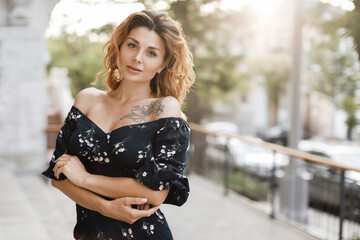 happy young woman walking in city street in sunset warm light. Smiling emotional girl outdoors in summer dress