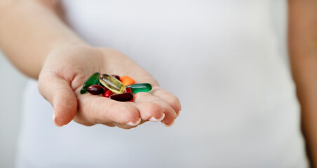 A woman's hand holds a handful of multicolored tablets. Medical confection, on a light background.