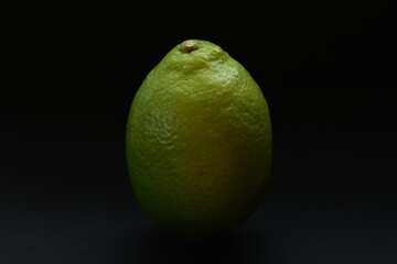 Fresh green lemon isolated on black background.