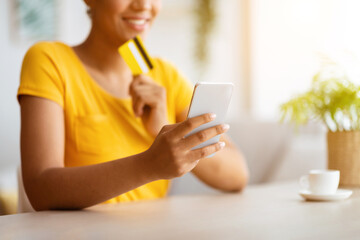 Black girl using phone and credit card at home