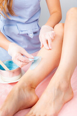 Sugar and waxing depilation of the feet in the beauty salon. Rid of hair on the legs. Sugaring. Master cosmetologist removing hair on the legs. Beautician in the spa center. Cosmetology concept.