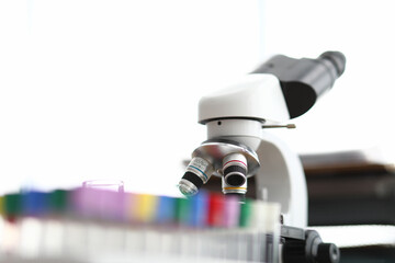 A microscope is standing next to empty test tubes. Accurate measurement results and chemical control analyzes