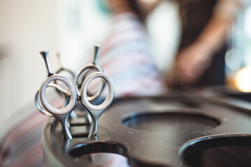 Professional barbers equipment with scissors in focus. Close-up of haircutting scissors and combs. High angle view of equipment on table. Focus is on tools in barbershop.