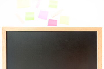 Set of colorful sticky notes next to a blackboard on white background