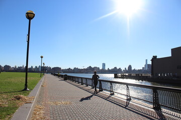 A person running jogging in a park in Hoboken, New Jersey - Manhattan New York Skyline - Maxwell Place Park