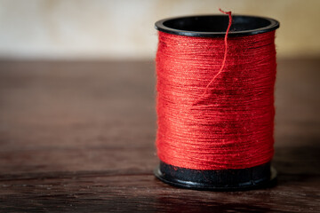 Red spool of thread on wood with copy space.