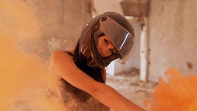 close up face woman biker posing looking camera waving orange smoke grenade slow motion