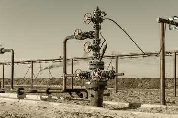 Petroleum well wellhead equipment. Hand valve with handwheel on the flow line. Oilfield site. Oil, gas industry concept. Industrial site background. Production oil. Multiple check valve gate armature.