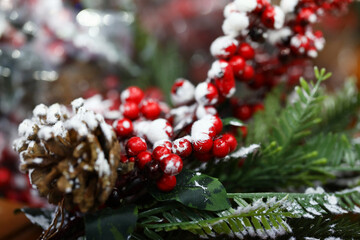 Christmas decoration with pine cone and green spruce branch. Red berries decorated with artificial snow