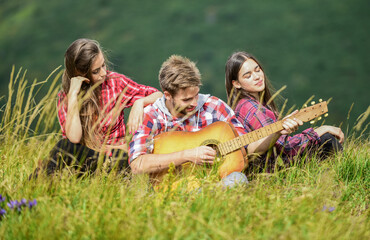 People relaxing on mountain top while handsome man playing guitar. Peaceful place. Melody of nature. Hiking tradition. Friends hiking with music. Singing together. Musical pause. Hiking entertainment