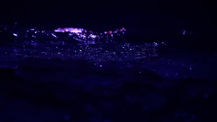 Waves and splashes in the dark water illuminated by blue light, in slow motion - Powered by Adobe