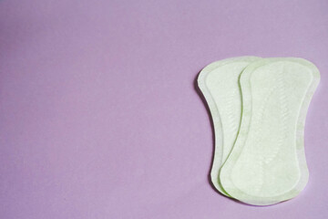 two white pads on a light purple background.  feminine hygiene during menstruation