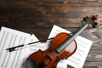 Violin, bow and note sheets on wooden table, flat lay. Space for text