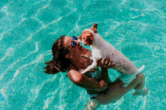 happy young woman and dog in a pool having fun. Summer time