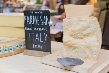 Large piece of Parmesan on wooden board with stone knife spatula. This is sample of cheese on...