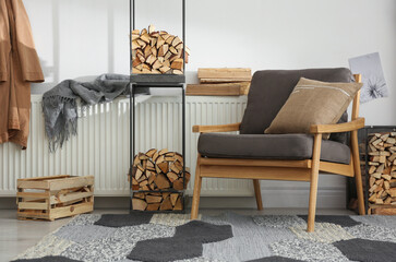 Firewood near armchair in stylish room interior