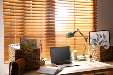 Comfortable workplace with laptop near window at home