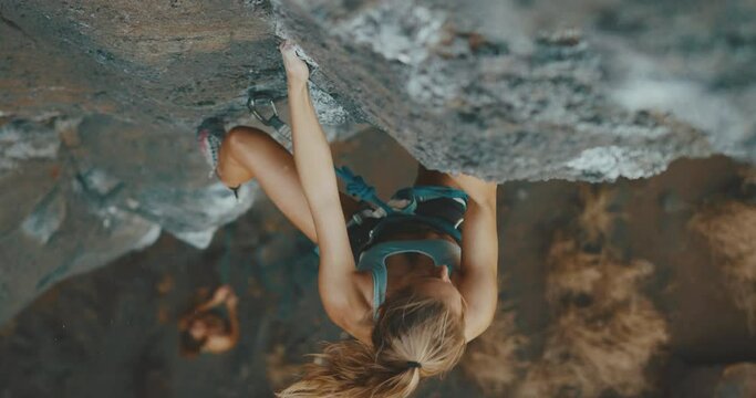 Beautiful strong sexy young woman rock climbing up cliff face, cinematic slow motion, fitness lifestyle