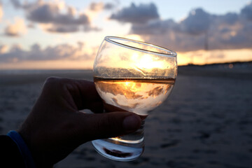 holding my drink against the sunset sun on the beach