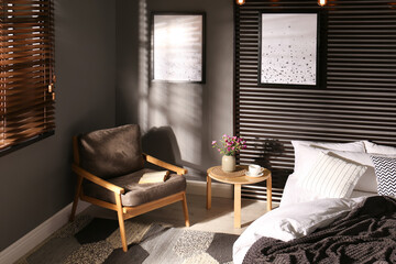 Comfortable bedroom with armchair and pictures on wall. Interior design