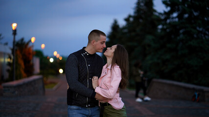 Portrait of happy couple. Young strong man and pretty girl in evenig in park