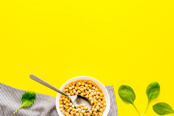 Raw chickpeas in bowl on yellow kitchen table from above copy space
