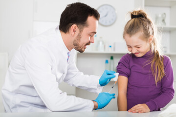 Fototapeta premium Male doctor using syringe to make injection to young female patient in hospital