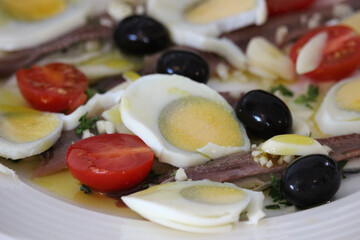 Anchovy salad with boiled egg, black olives and tomato
