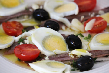 Anchovy salad with boiled egg, black olives and tomato