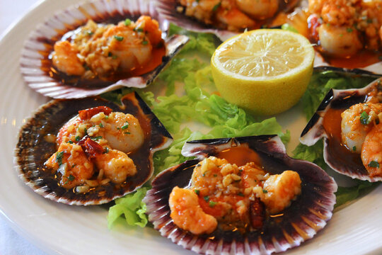 "Zamburi&ntilde;as" (Chlamys varia) cooked on the grill with a lemon slice. They are also called variegated scallop or scallop