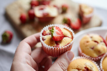 Strawberry muffin with fresh strawberries in hand, sweet summer dessert