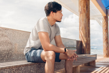 Lonely Asian man sitting in the hut by the sea chilling the atmosphere.