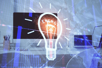 Computer on desktop in office with bulb icon hologram. Double exposure. Concept of idea.