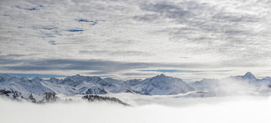 Fototapeta na wymiar Snow covered mountains with inversion valley fog and trees shrouded in mist. Panoramic snowy winter landscape in Alps, Allgau, Kleinwalsertal, Bavaria, Germany.
