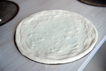 Preparation of dough for baking pizza on the table.