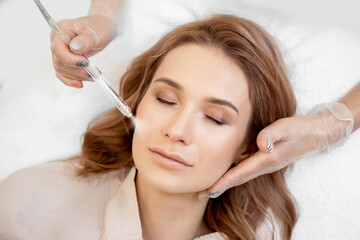 Naklejka premium Procedure Non contact cleaning skin of face from blackheads, acne. Doctor performs body are of young woman in clinic