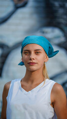 Young pretty girl in white shirt and blue head scarf on graffiti background