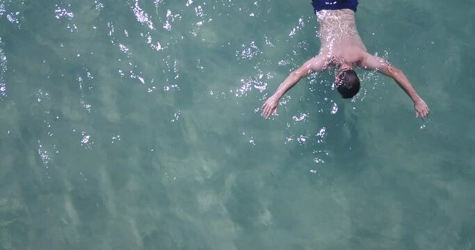 Male body floating in water. Aerial drone shot of drowned guy in the sea. Turquoise clear sea water