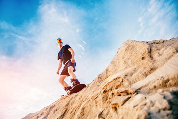 Extreme descent sand on snowboard in desert. Male snowboarder on dunes