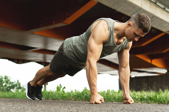 Muscular man is doing push-ups during calisthenic workout on a street